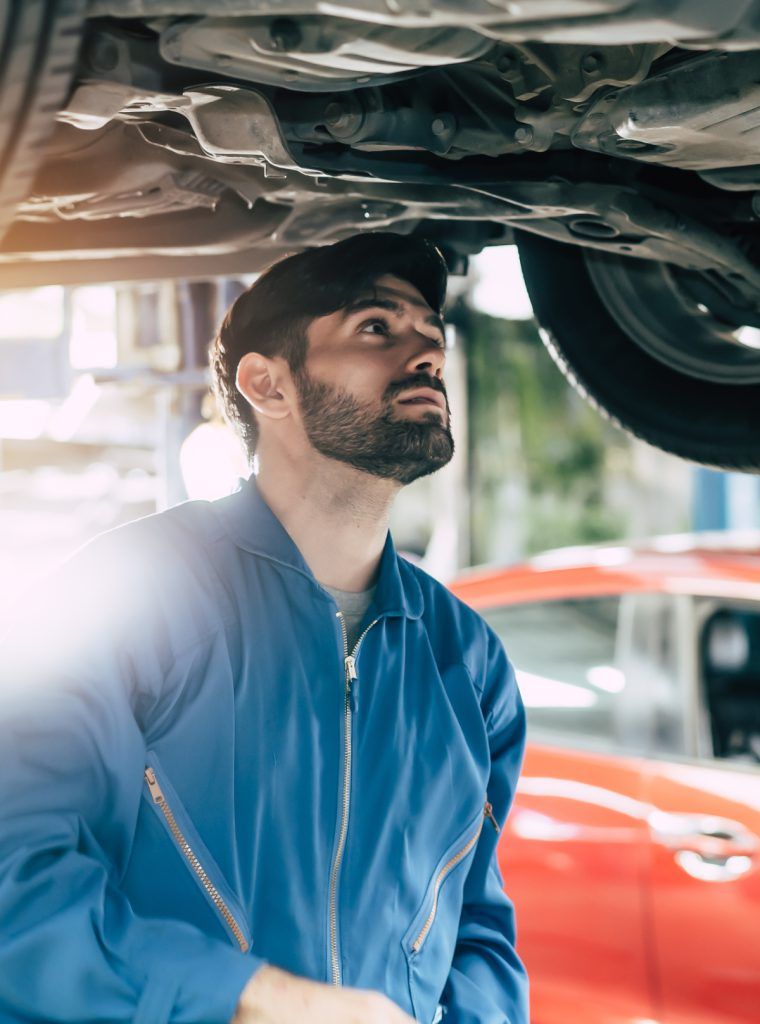 Auto Mechanic looking underneath a vehicle during an inspection - MOT Testing Liverpool